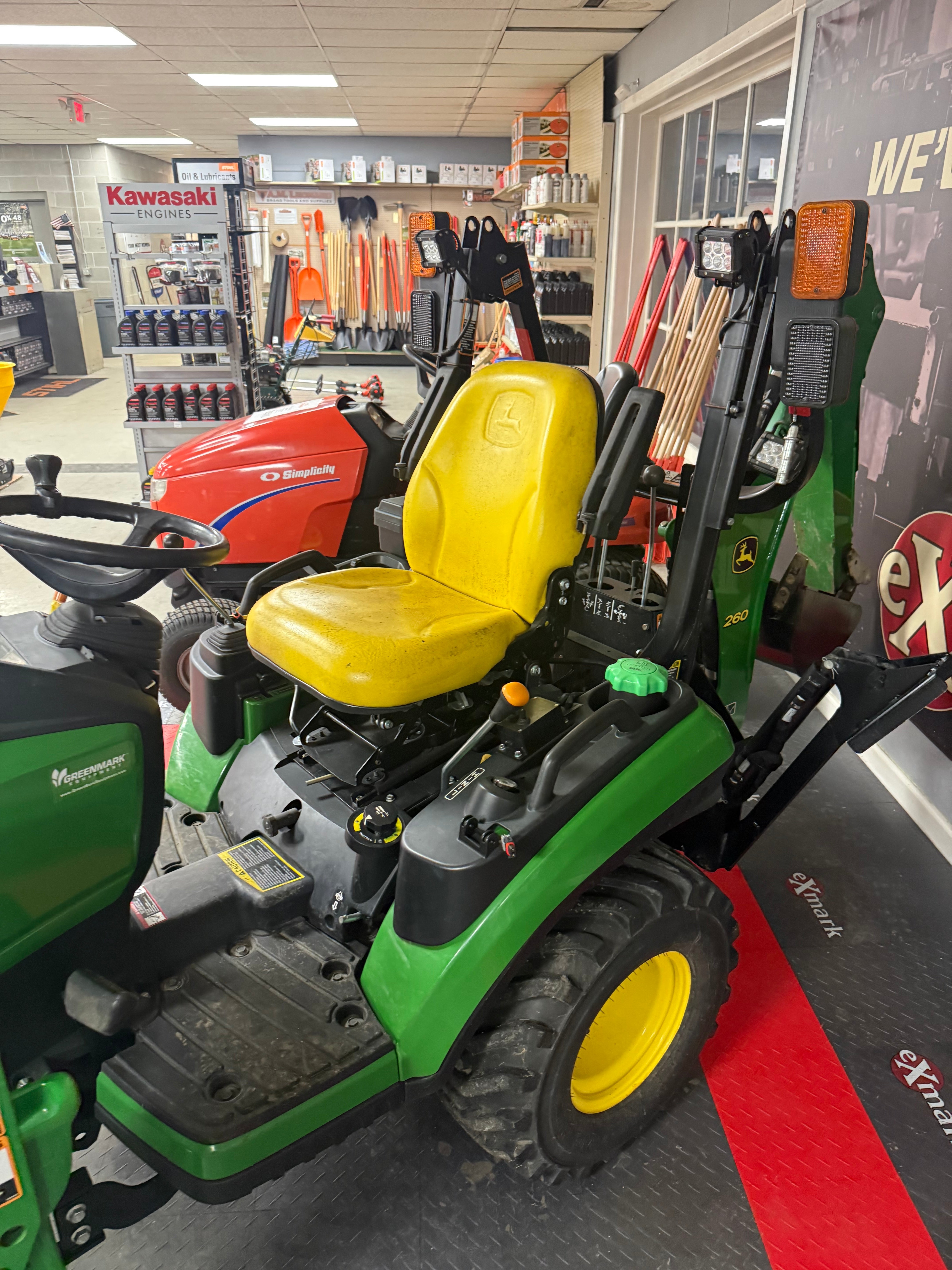 Green and yellow lawn mower in a showroom setting
