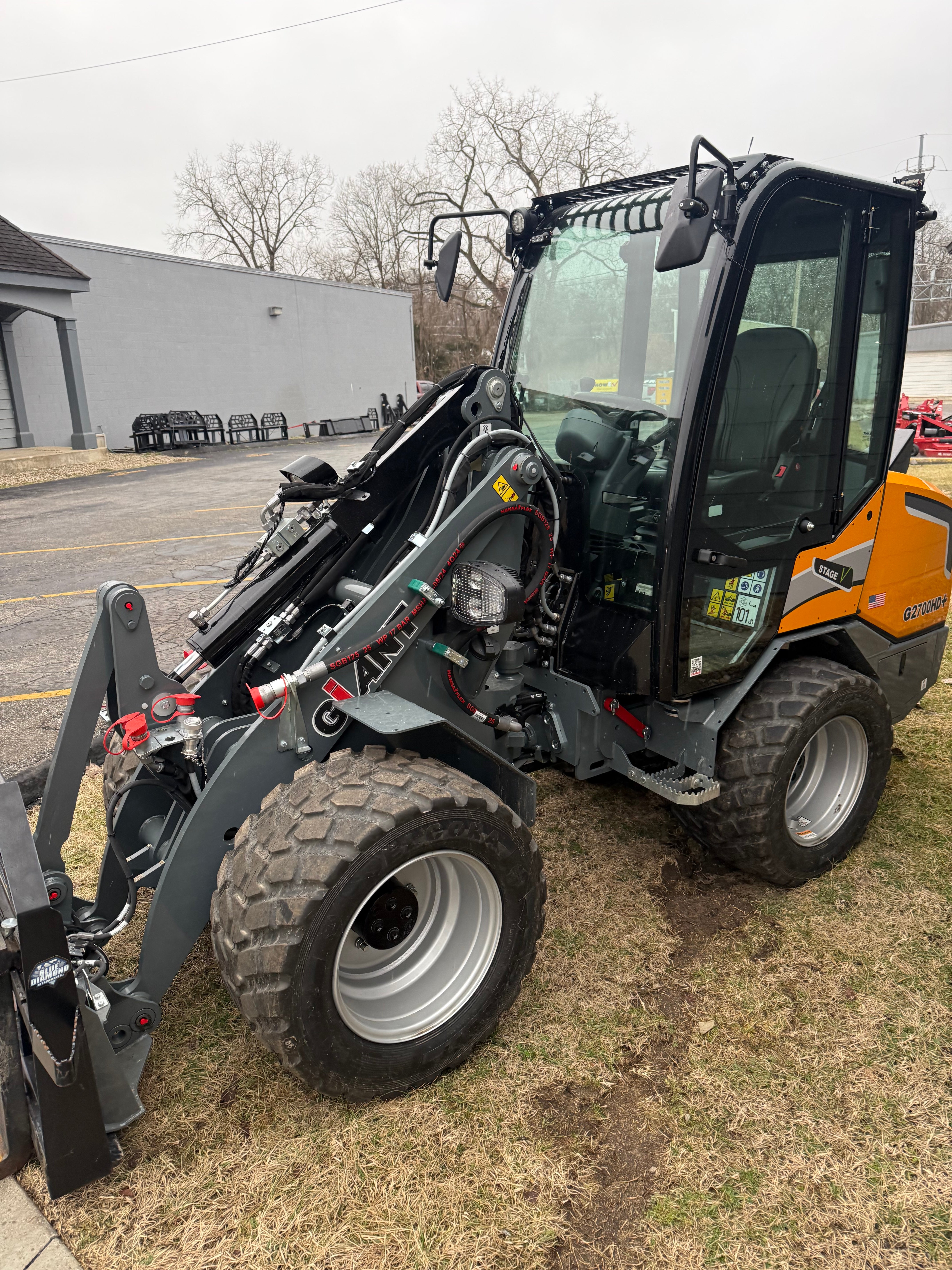 Skid steer loader on a grassy area with a building in the background