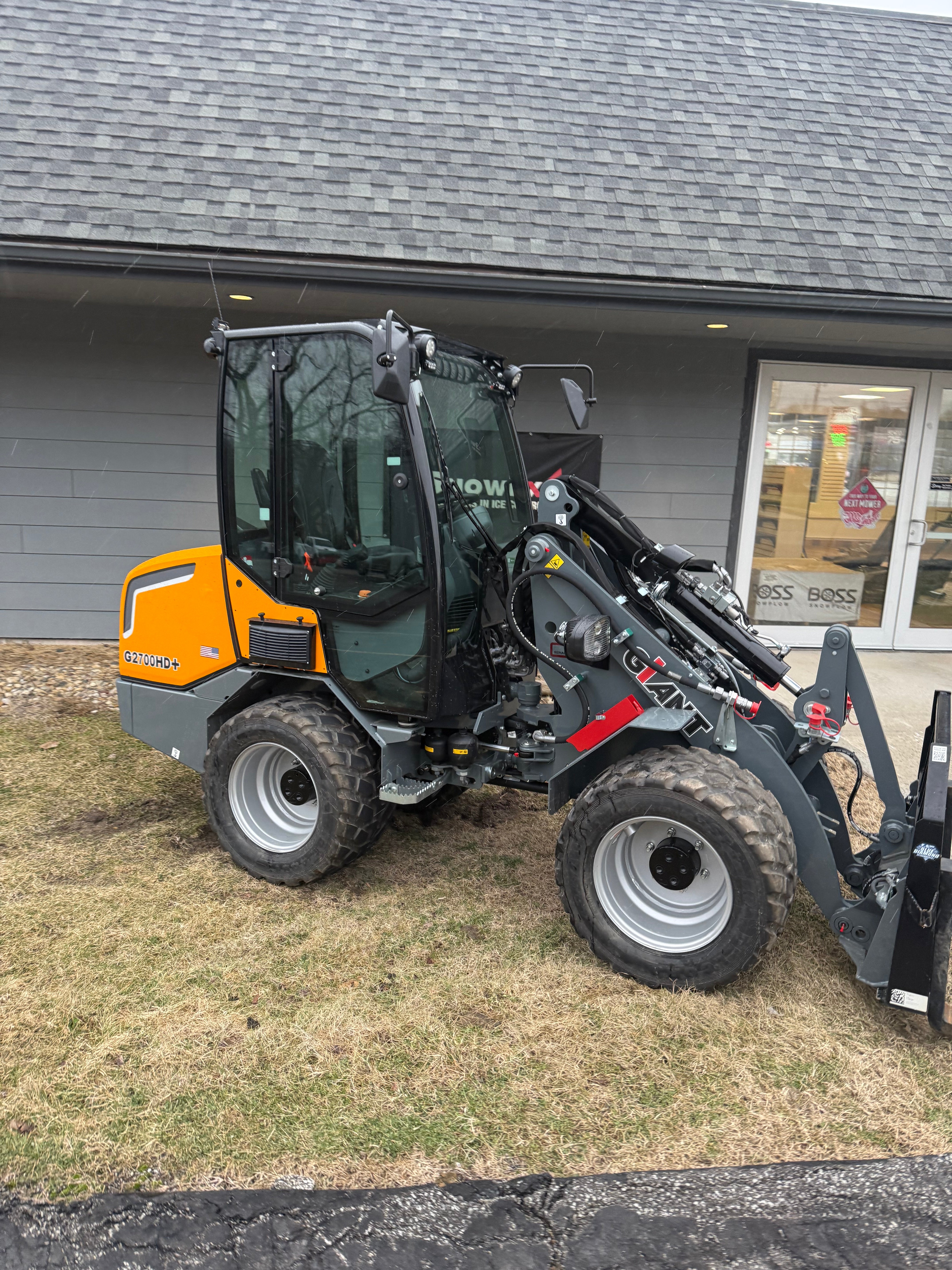 Backhoe loader parked on a grassy area next to a building.