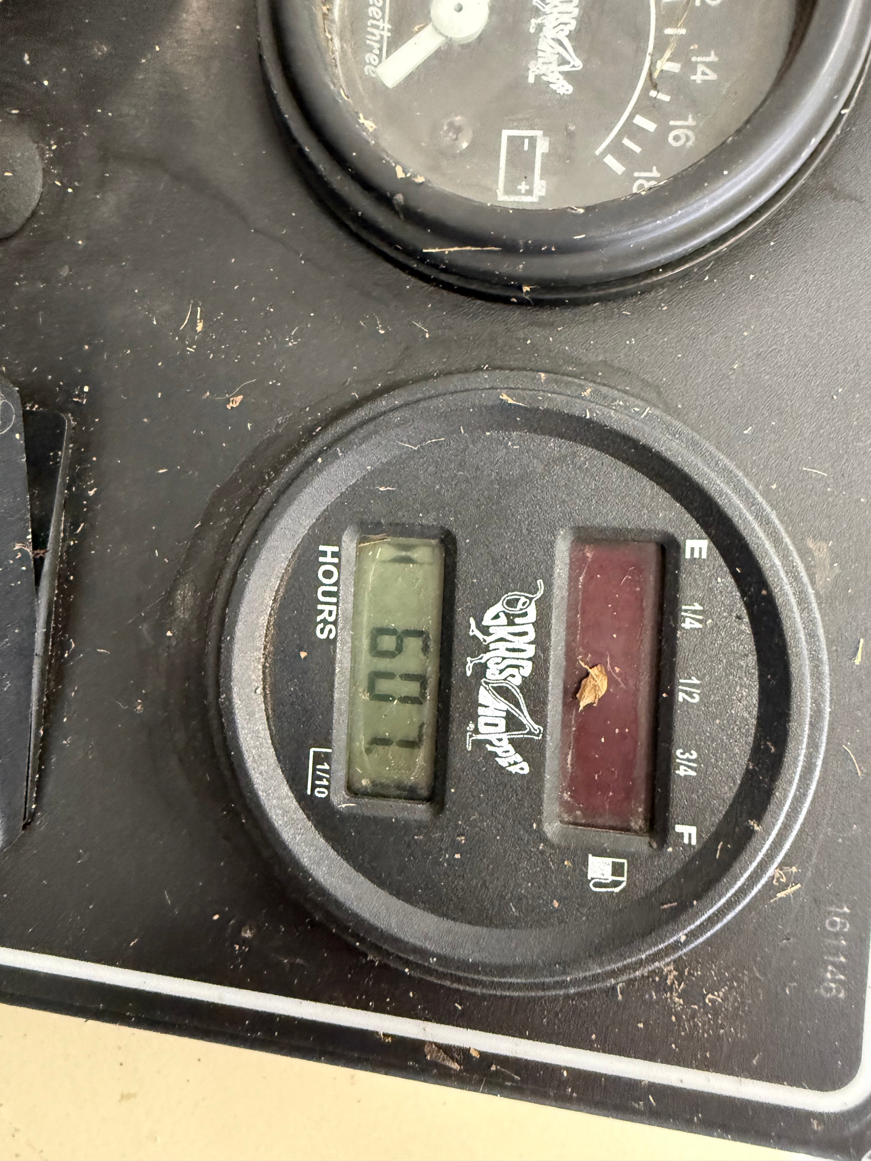 Close-up of a vehicle's dashboard with a hours counter and fuel gauge.