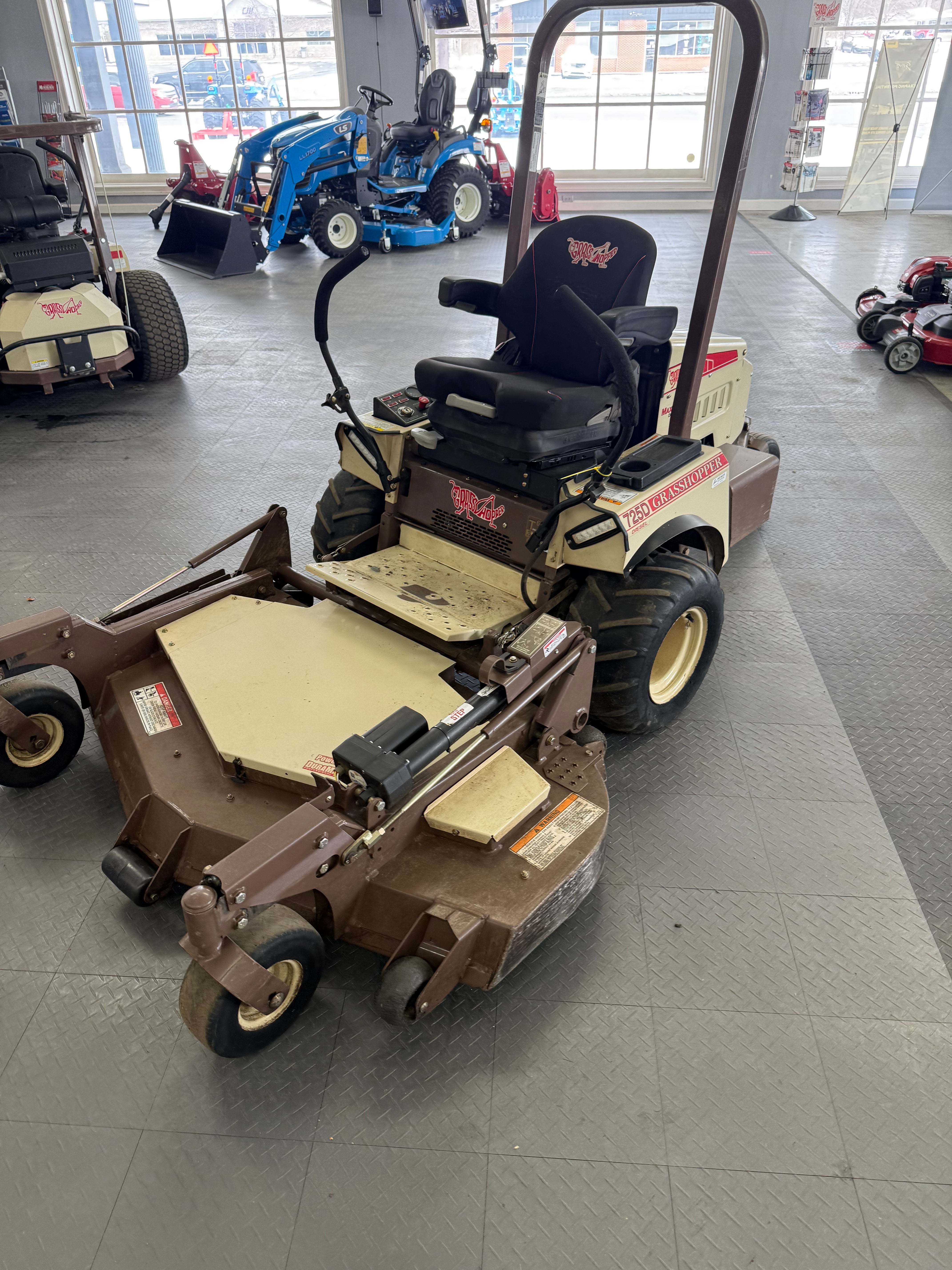 Two lawn mowers on a tiled floor in a showroom setting