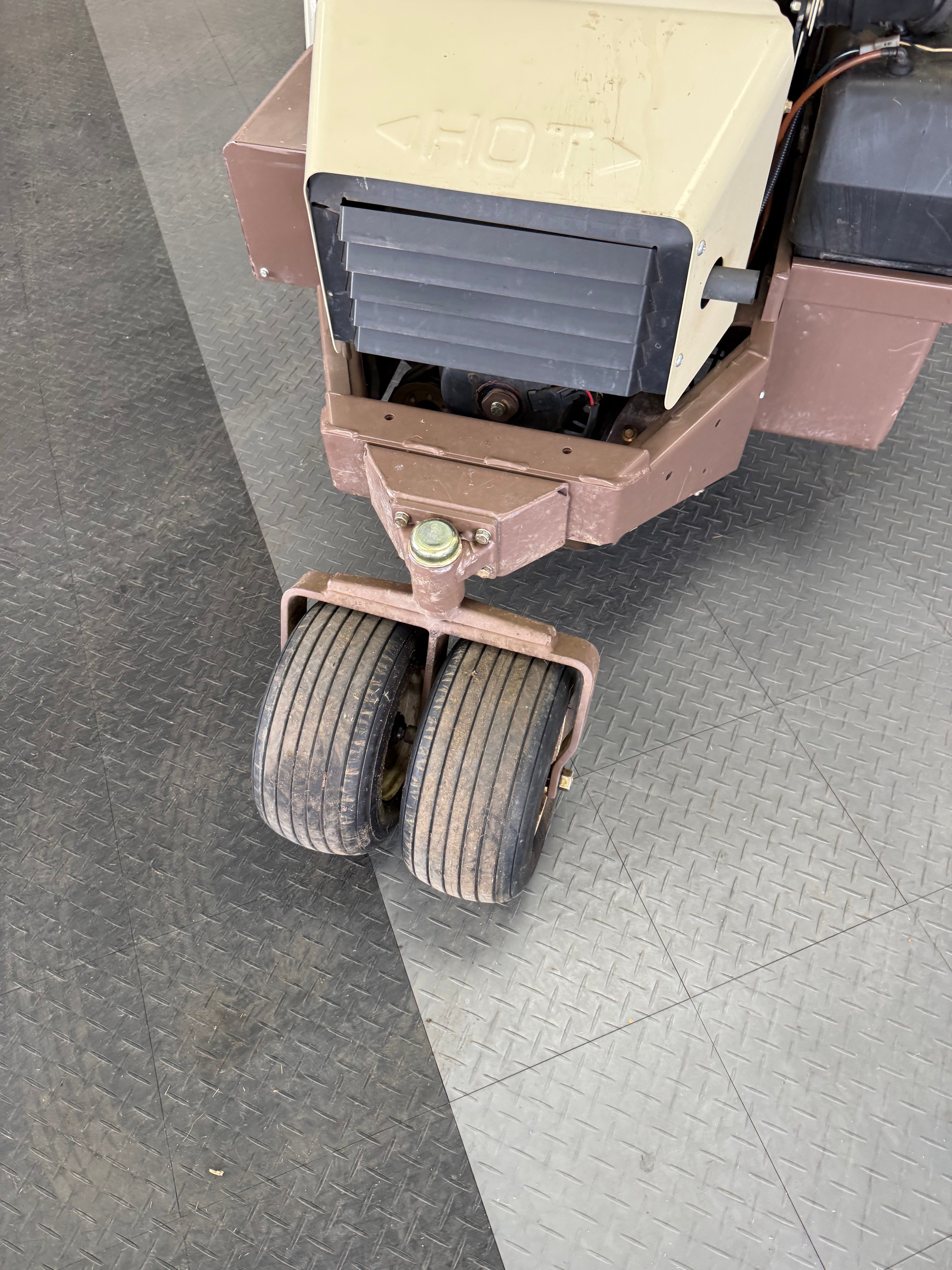 Close-up of a forklift truck's rear wheel and suspension system on a textured floor.
