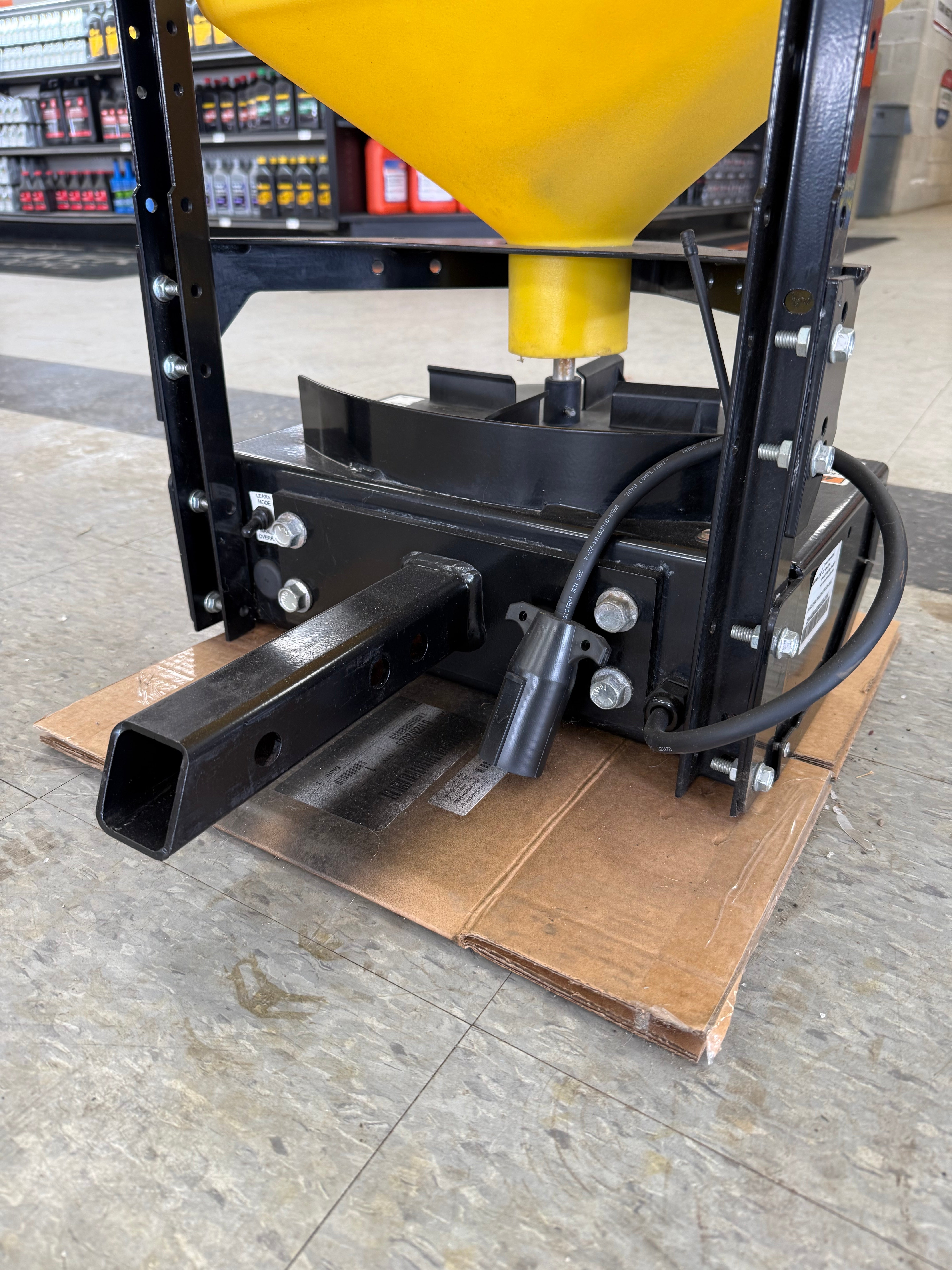 Mechanical component with yellow funnel and black metal parts on a cardboard box