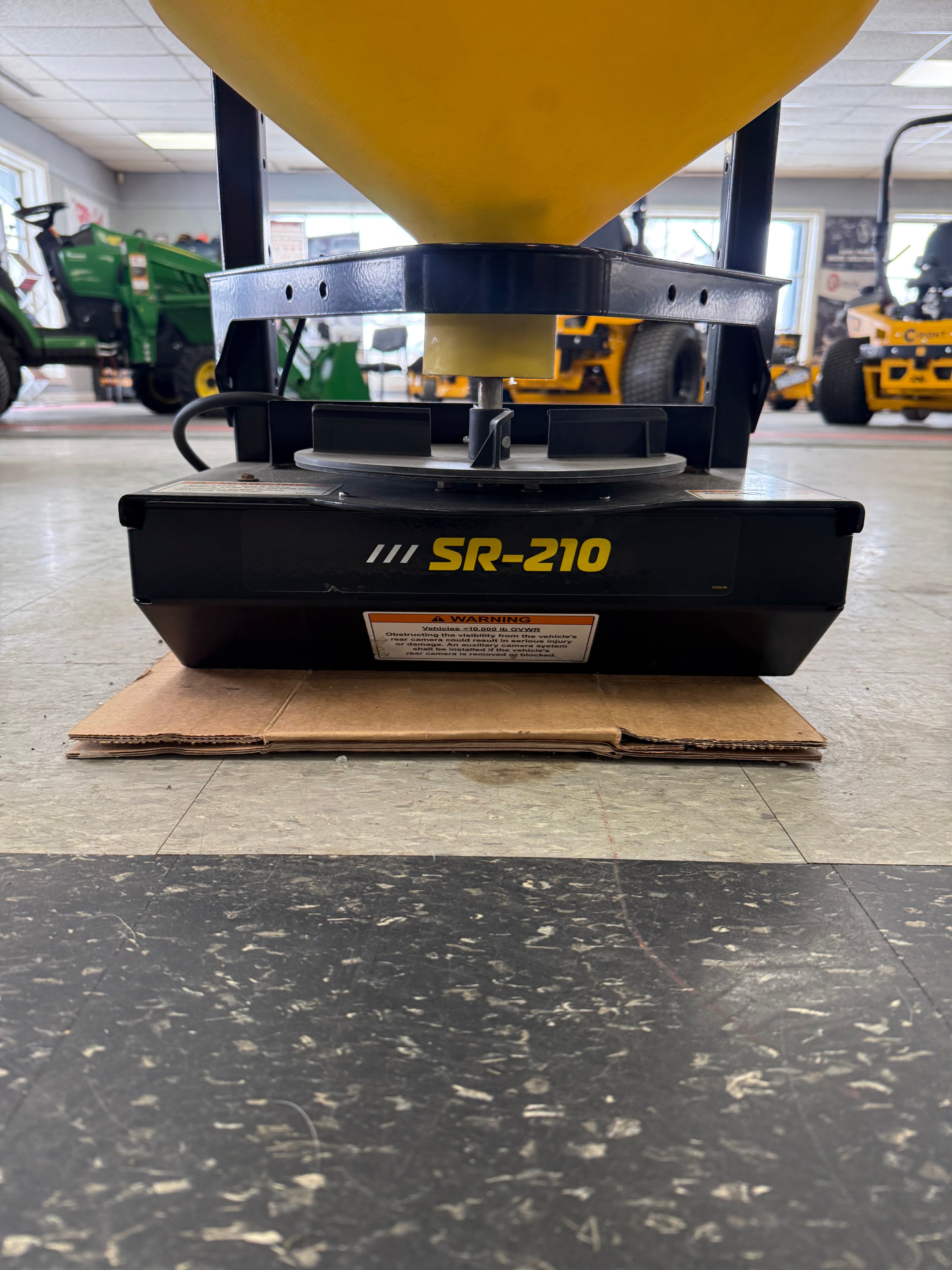Snow blower on a tiled floor with a cardboard box underneath