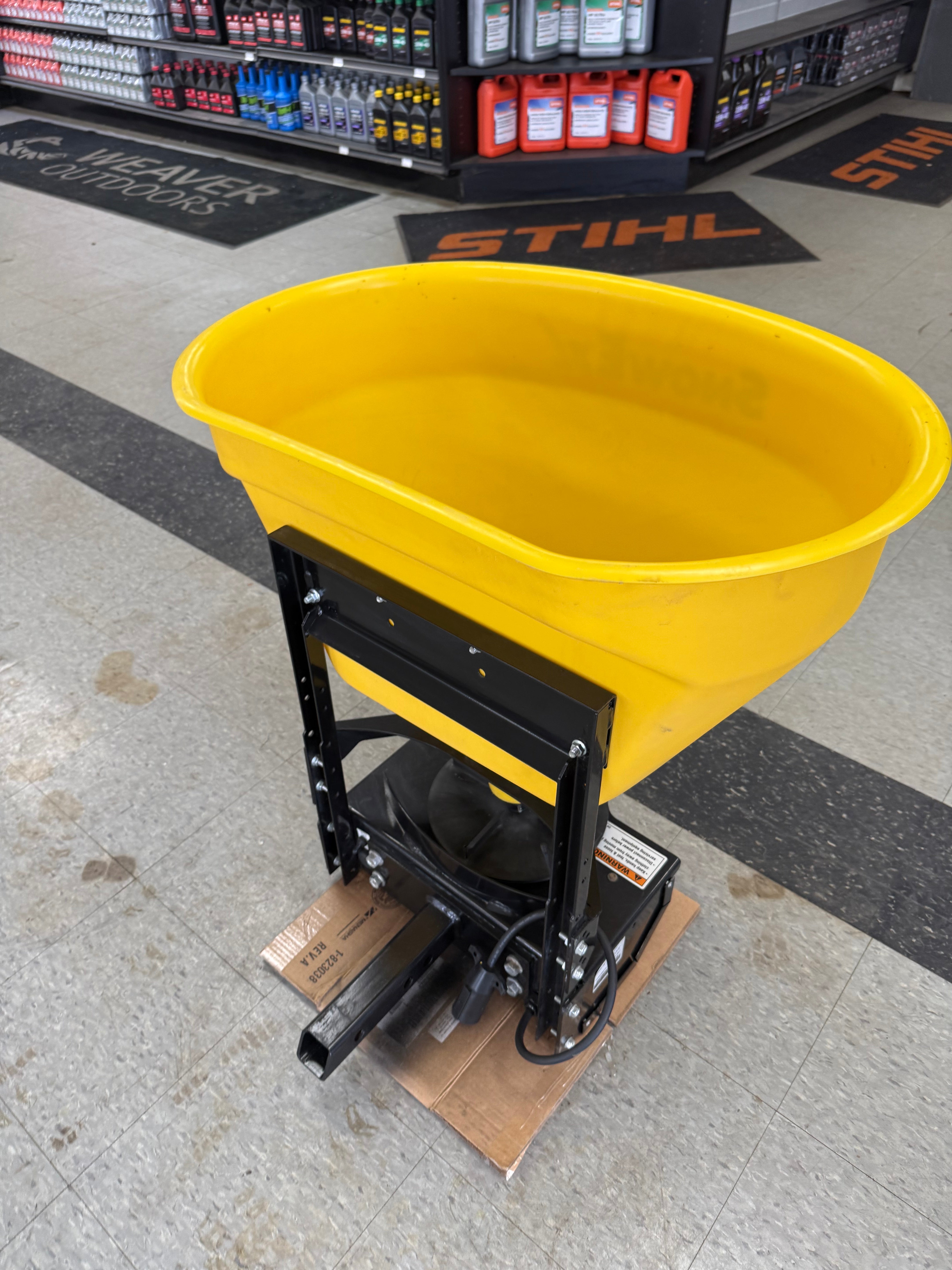 Yellow forklift attachment on a concrete floor with tools in the background