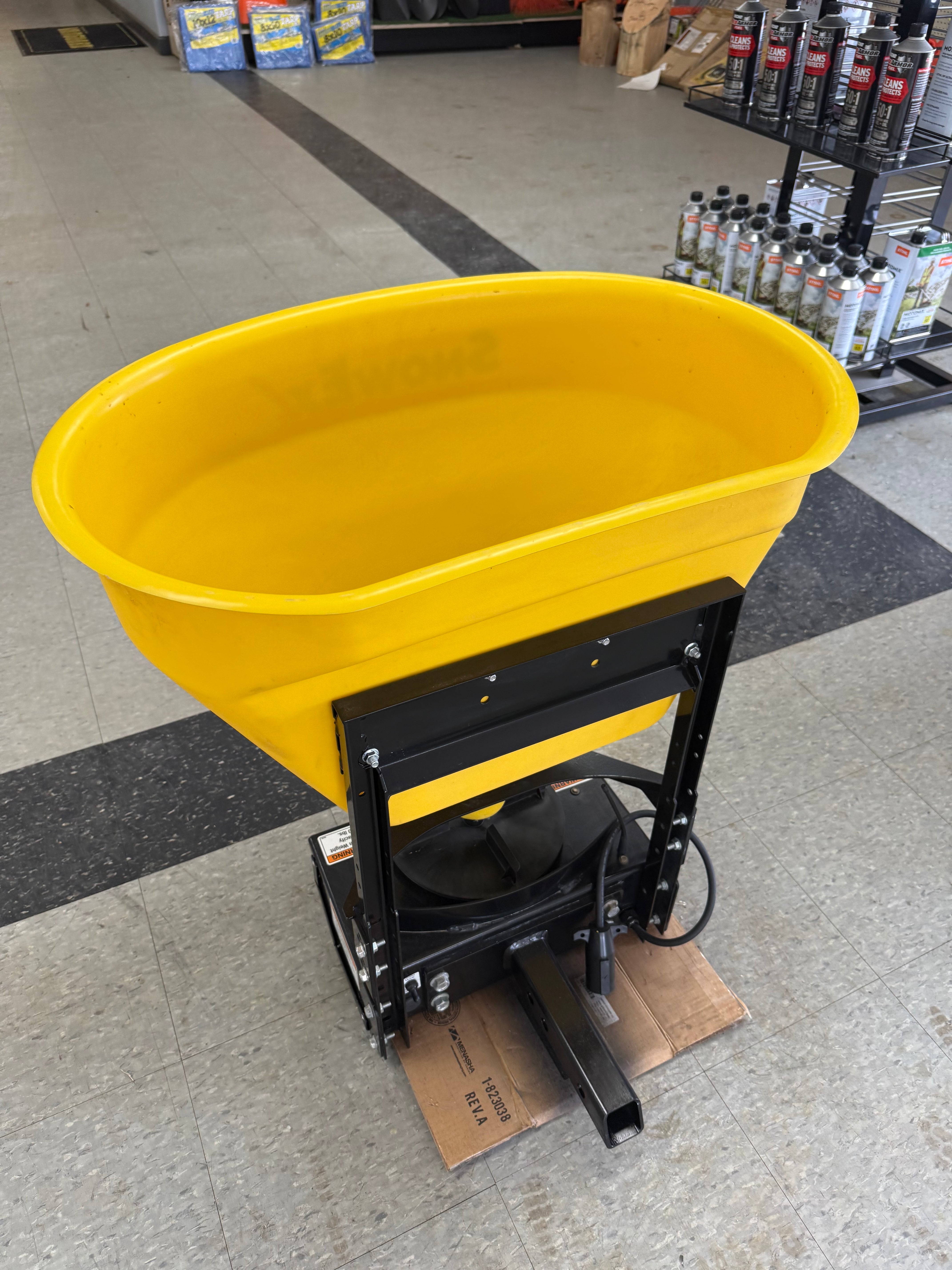 Yellow metal bowl with black metal stand on a gray floor