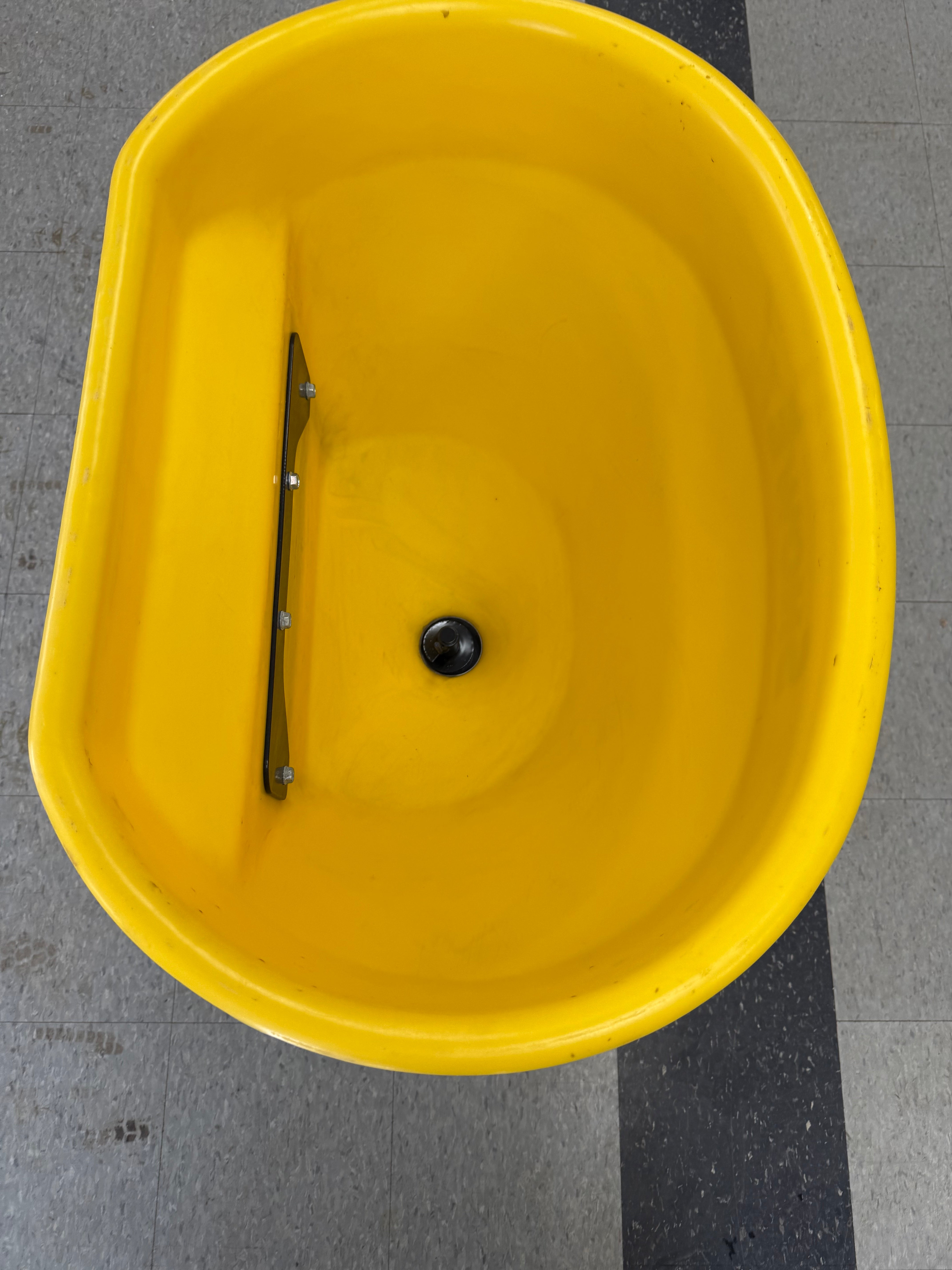 Yellow bucket with a black object inside on a checkered floor