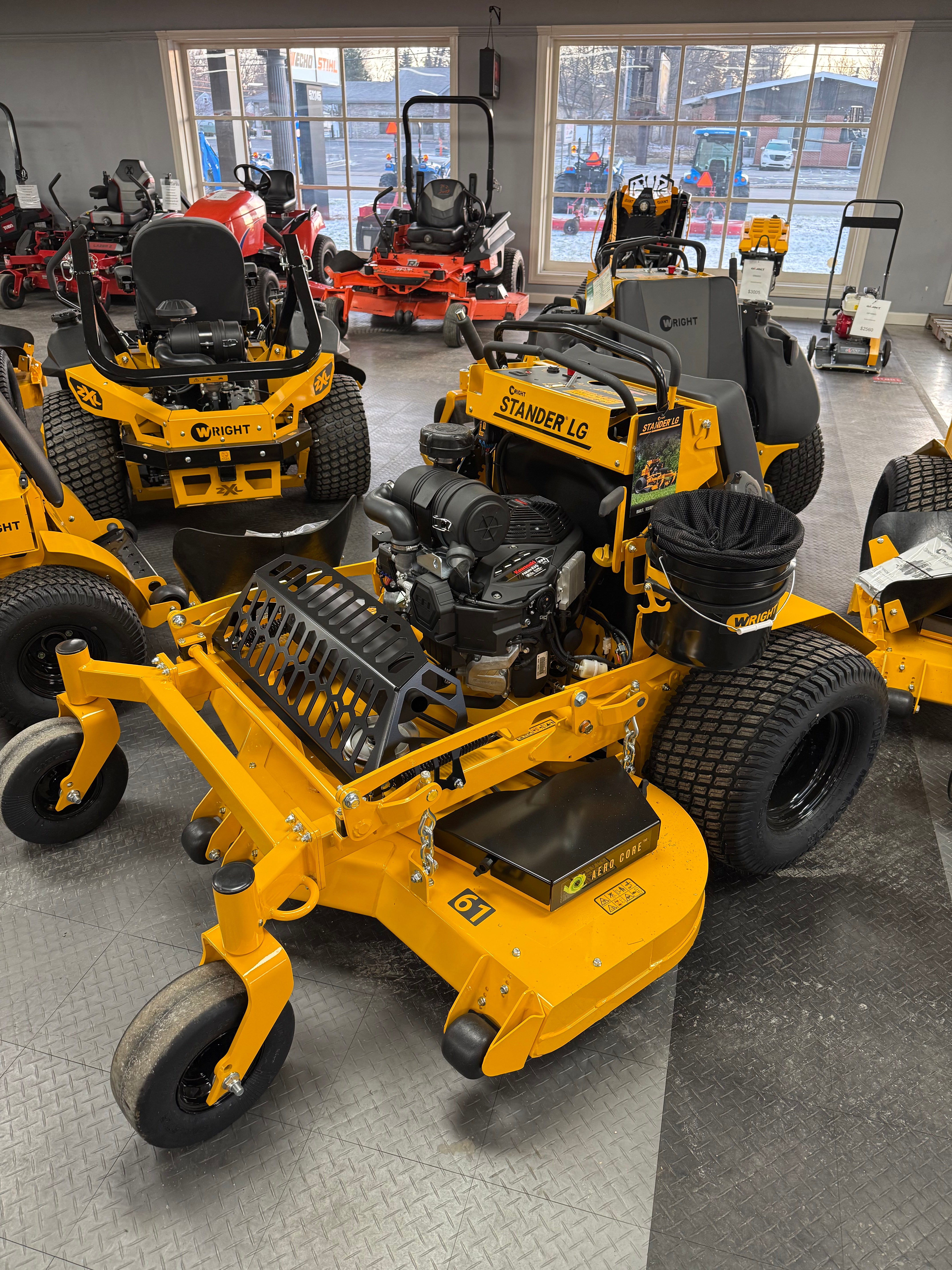 Yellow lawn mower on display in a showroom with large windows.